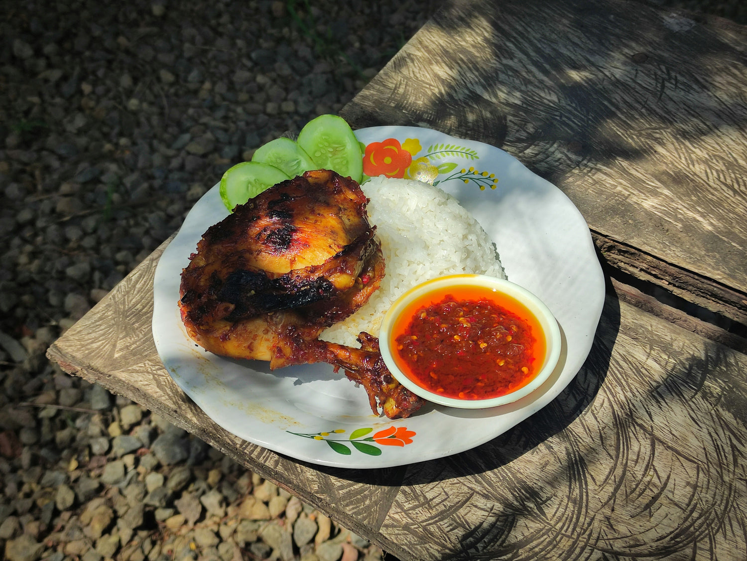 Hähnchenkeule mit Reis auf Teller; daneben kleine Schale Sambal Oelek.