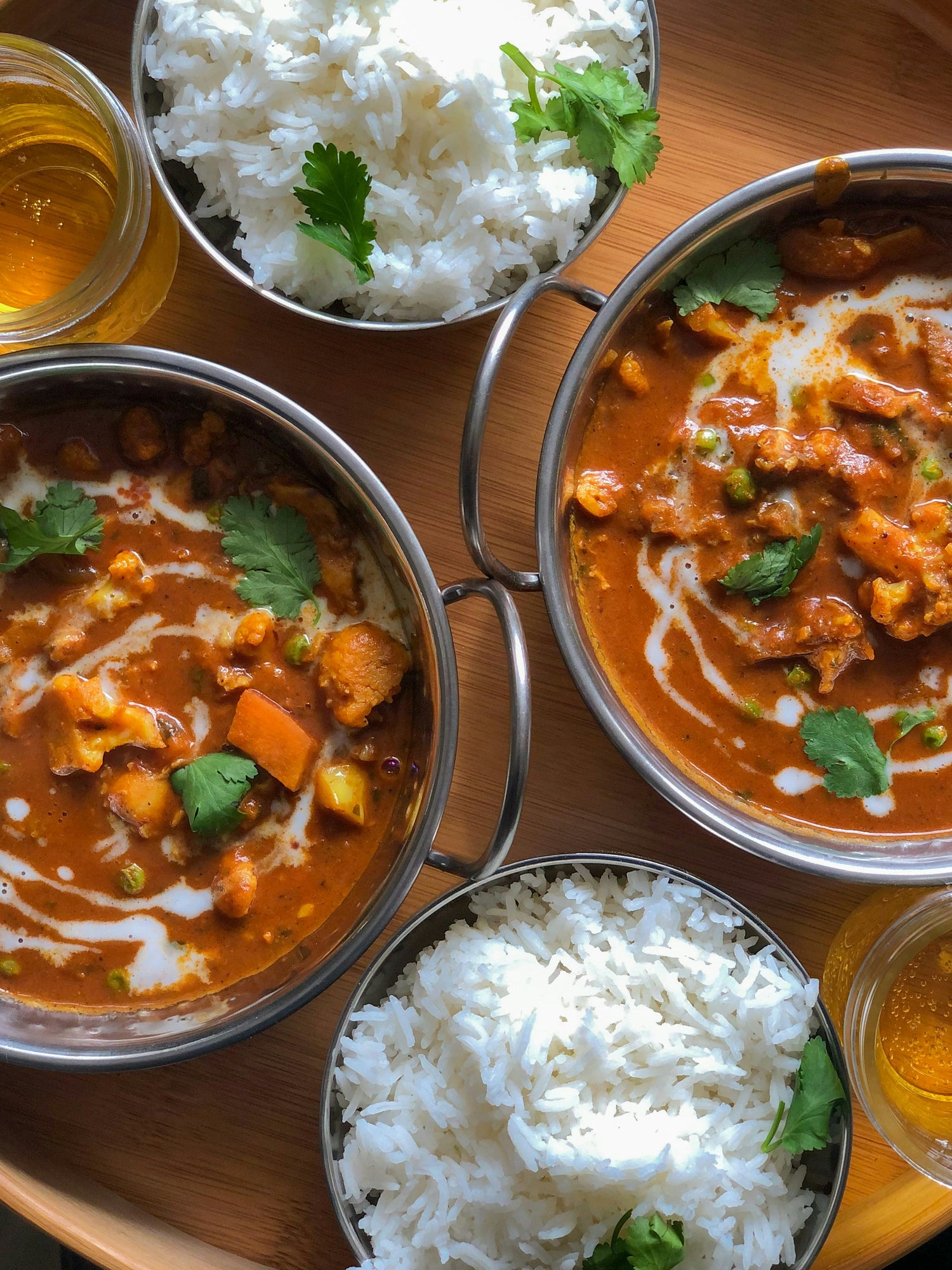 Indonesisches Gulasch in kleinen Töpfen, daneben Schalen mit Reis -servierfertig.