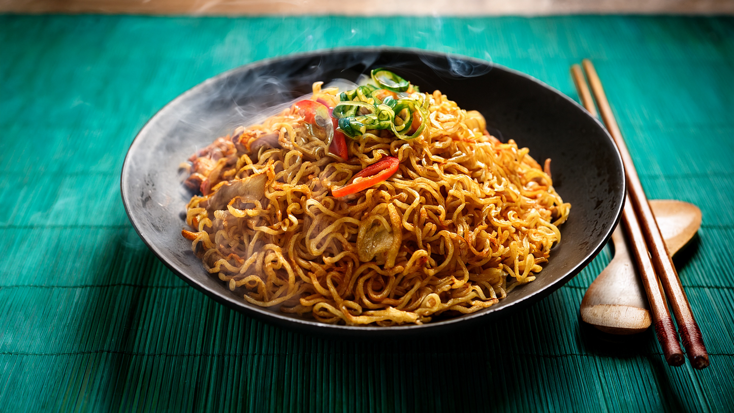 Mie Goreng - gebratene Nudeln mit Gemüse, glänzend glasiert, heiß serviert.