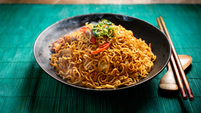 Mie Goreng - gebratene Nudeln mit Gemüse, glänzend glasiert, heiß serviert.
